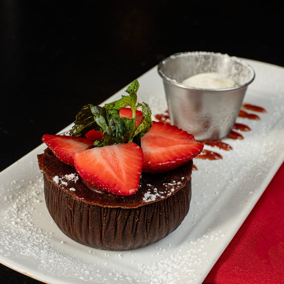 Chocolate lava cake with sliced strawberries, mint, powdered sugar, and a side of ice cream.